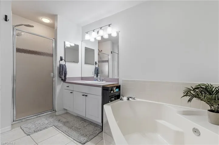 Full bath featuring a garden tub, a stall shower, vanity, and light tile patterned floors
