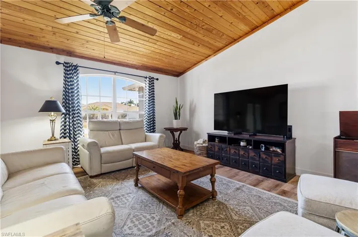 Living area with a ceiling fan, wood finished floors, and a vaulted wooden ceiling