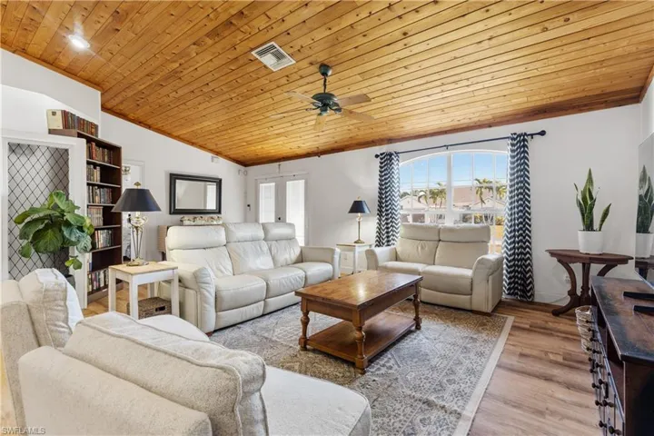 Living area with a vaulted wooden ceiling, ceiling fan, light wood-type flooring, and french doors