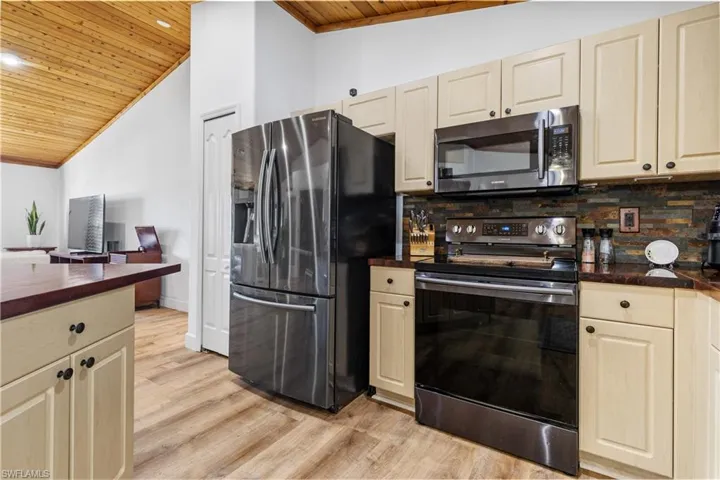 Kitchen with stainless steel appliances, a vaulted wood ceiling, light wood-type flooring, tasteful backsplash, and recessed lighting