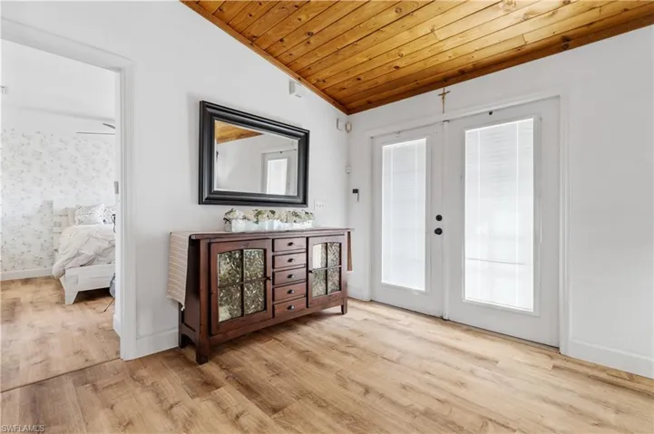 Foyer entrance with french doors, a vaulted wood ceiling, and light wood-style flooring