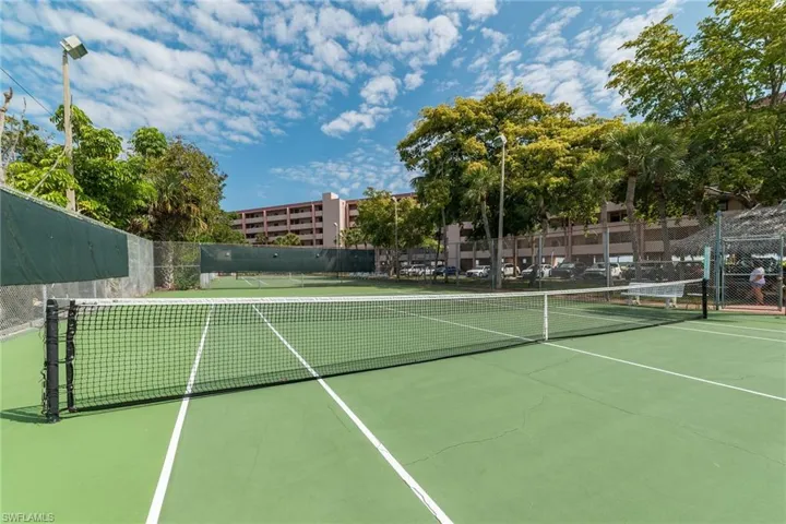 View of tennis court featuring community basketball court and fence