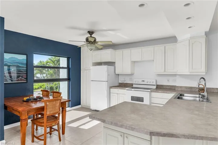 Kitchen featuring a sink, white cabinetry, white appliances, and light tile patterned flooring