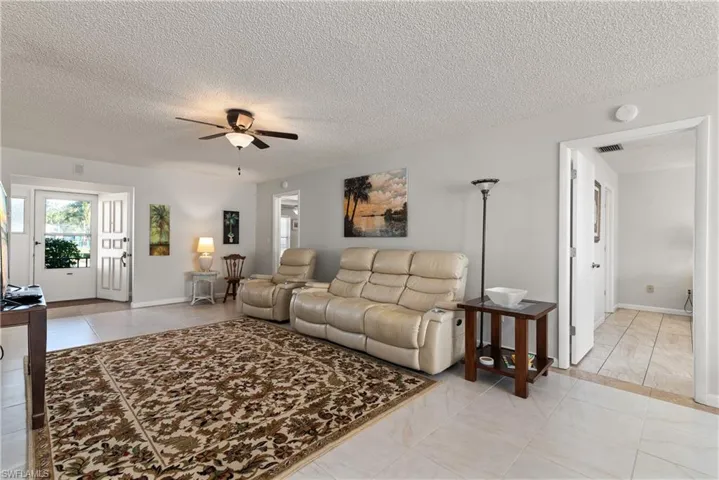 Living area featuring a ceiling fan, light tile patterned floors, and a textured ceiling