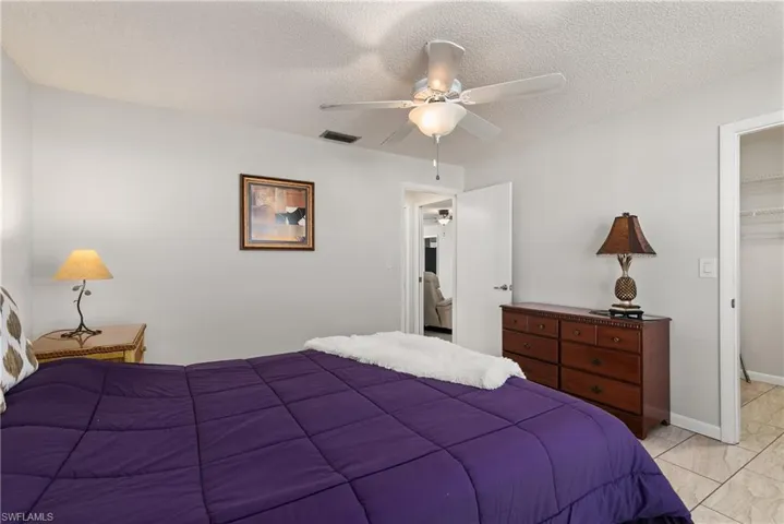 Bedroom with a textured ceiling, a ceiling fan, and a spacious closet