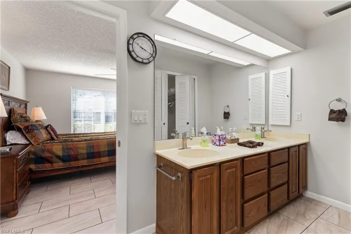 Full bath with double vanity, a textured ceiling, and connected bathroom