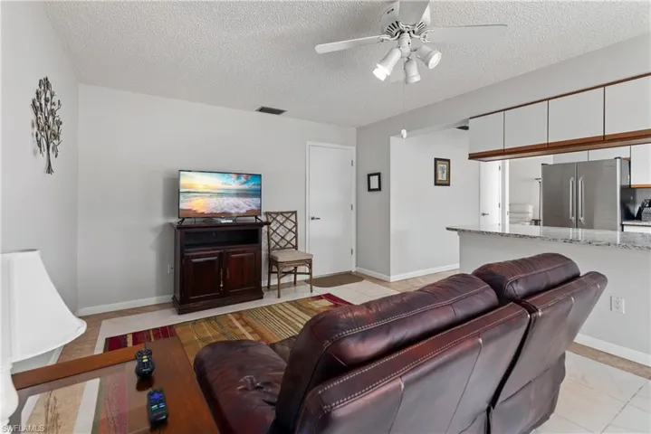 Living area featuring a textured ceiling, a ceiling fan, and light tile patterned floors
