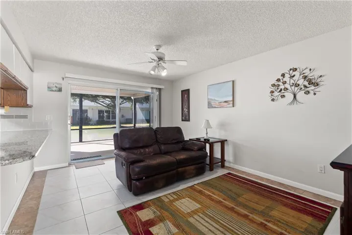 Living room featuring light tile patterned flooring, ceiling fan, and a textured ceiling