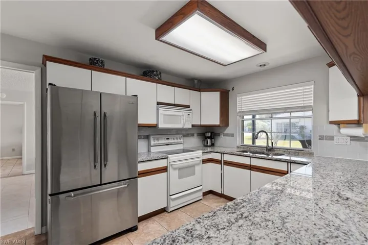 Kitchen featuring white appliances, white cabinetry, tasteful backsplash, and brown cabinets