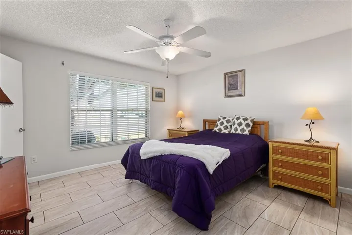 Bedroom featuring a textured ceiling, ceiling fan, and wood finish floors