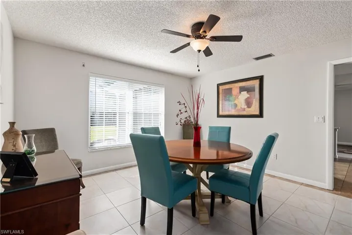 Dining space with a textured ceiling, light tile patterned flooring, and ceiling fan