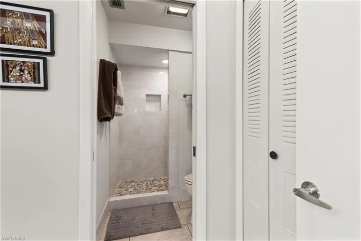 Bathroom featuring a tile shower and a closet