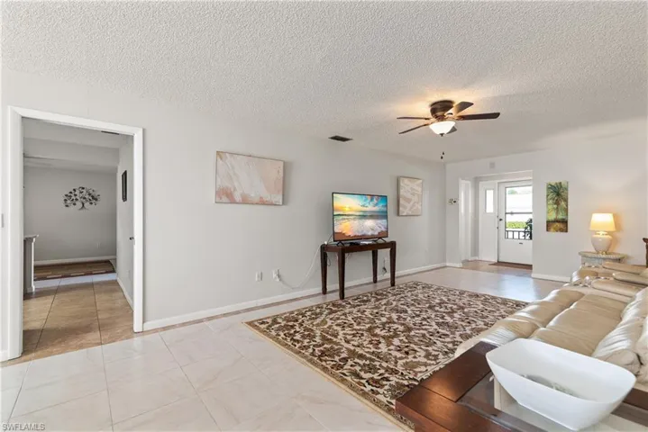 Living area featuring tile patterned floors, ceiling fan, and a textured ceiling