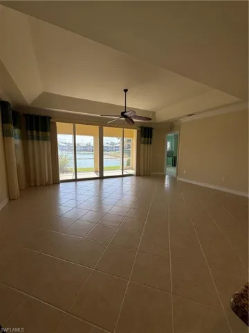 Tiled spare room with a raised ceiling, a water view, ceiling fan, and plenty of natural light