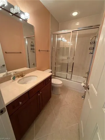 Bathroom featuring vanity, light tile patterned flooring, and combined bath / shower with glass door