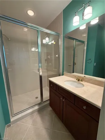 Full bath featuring a stall shower, vanity, and light tile patterned floors