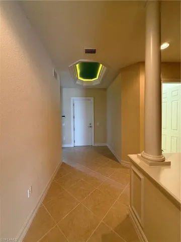 Hall featuring light tile patterned flooring and a textured wall