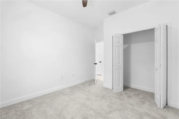 Unfurnished bedroom featuring light carpet, a closet, and ceiling fan