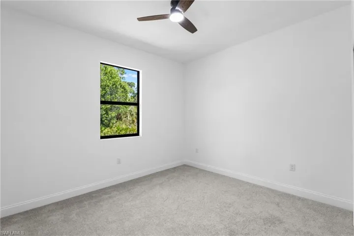 Carpeted spare room with baseboards and ceiling fan
