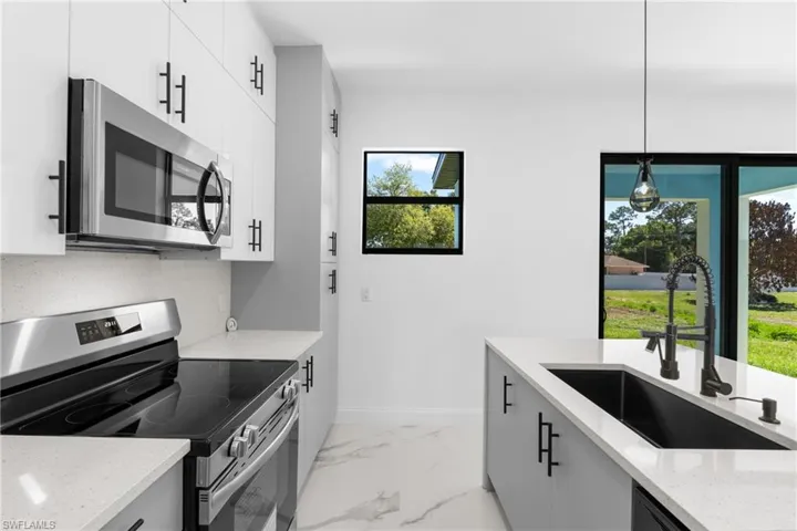 Kitchen with stainless steel appliances, light stone counters, hanging light fixtures, and modern cabinets