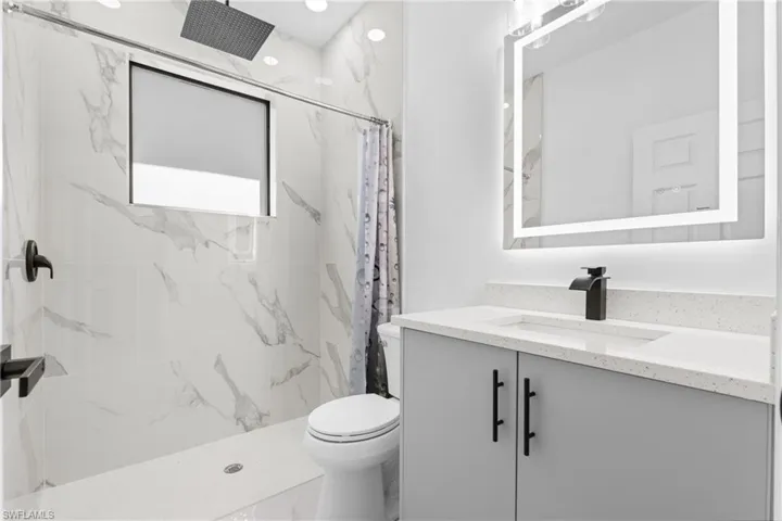 Full bathroom featuring vanity and a marble finish shower