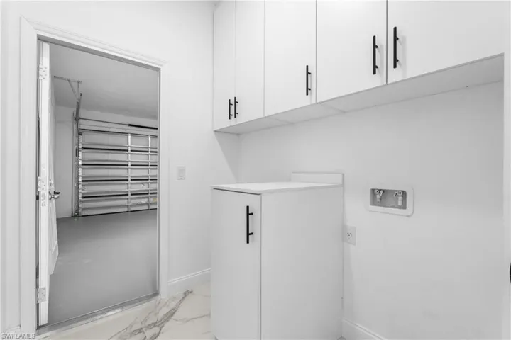 Laundry area featuring cabinet space, light marble finish floors, and washer hookup