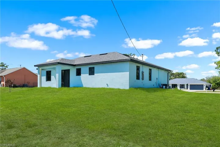 Rear view of property featuring a yard, stucco siding, and a garage