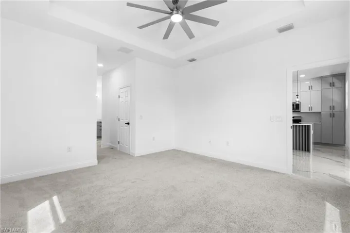 Unfurnished room featuring a tray ceiling, a ceiling fan, light carpet, and recessed lighting