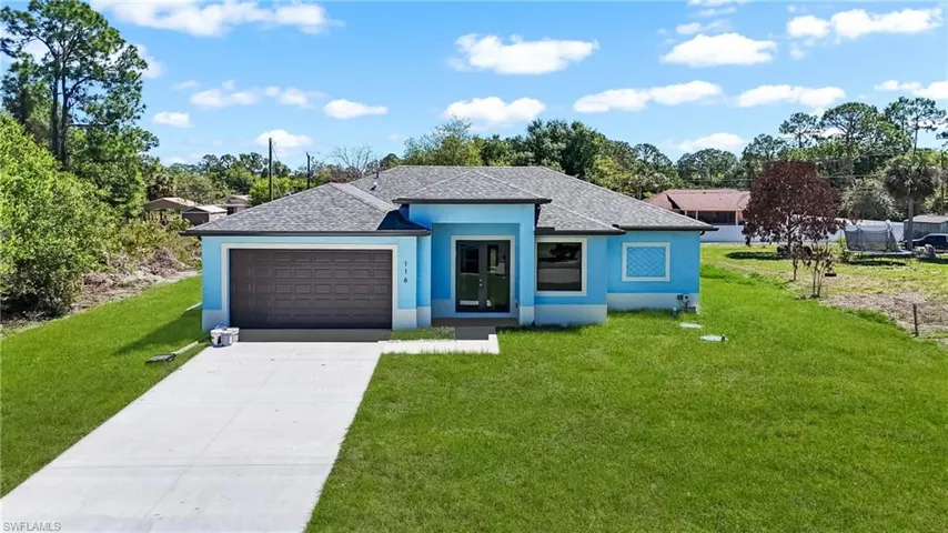 View of front of property featuring a front yard, a garage, driveway, and a shingled roof