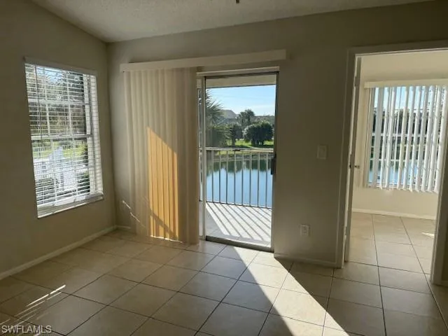Unfurnished room featuring a water view, a textured ceiling, and light tile patterned floors