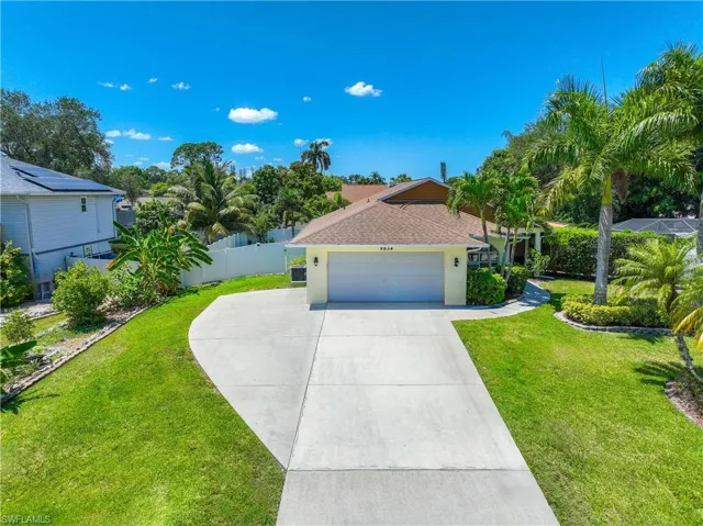 View of front of house with a oversized driveway and a front lawn
