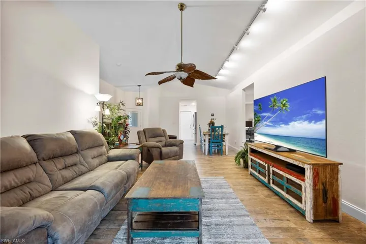 Living room with wood-style tile floors, track lighting, and ceiling fan
