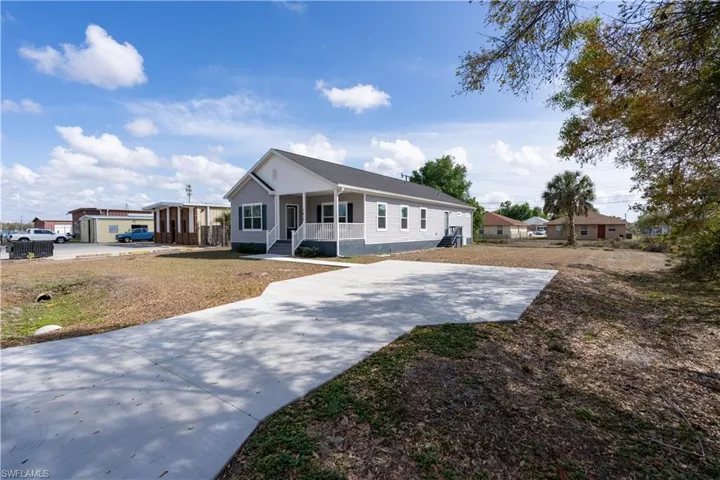 View of front facade with covered porch, driveway, and a front lawn