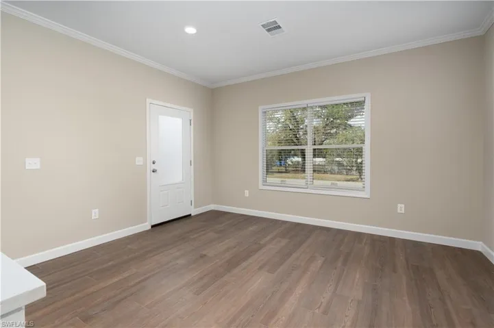 Unfurnished room with dark wood-style flooring, crown molding, and recessed lighting