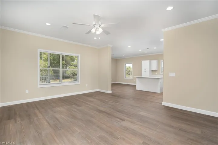 Unfurnished living room featuring ceiling fan, dark wood-style flooring, recessed lighting, and crown molding