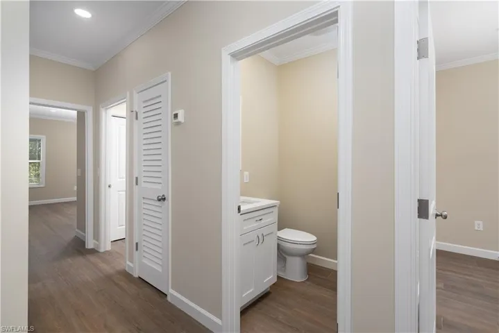 Bathroom with ornamental molding, vanity, dark wood-style flooring, and recessed lighting