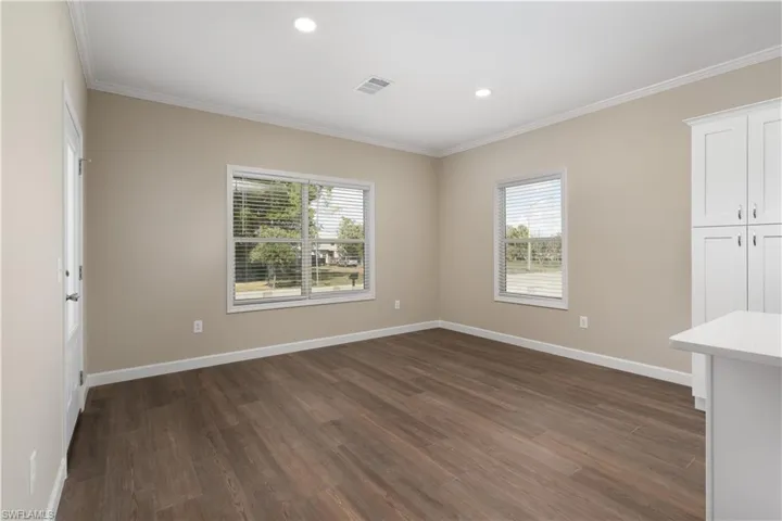 Unfurnished room featuring dark wood-style floors, recessed lighting, and ornamental molding