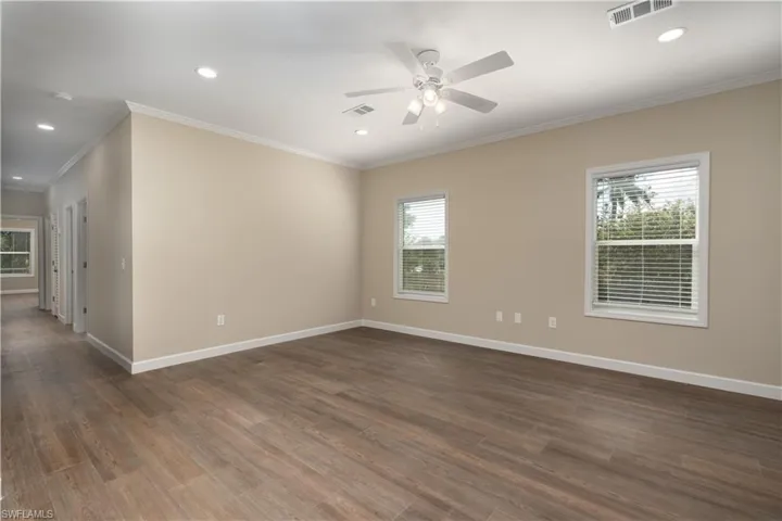 Spare room featuring plenty of natural light, recessed lighting, a ceiling fan, dark wood-type flooring, and crown molding