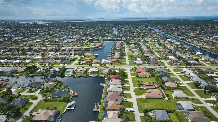Aerial view of property and surrounding area featuring a large body of water and nearby suburban area