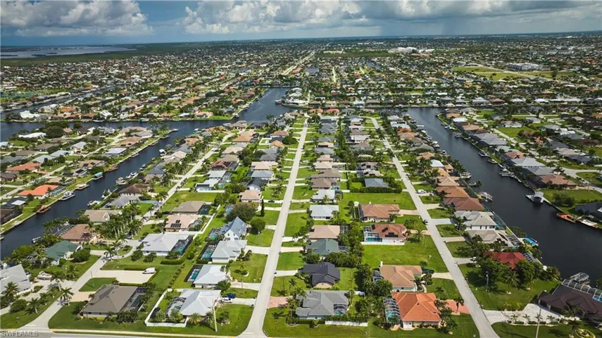 Aerial view of property and surrounding area featuring a nearby body of water and nearby suburban area