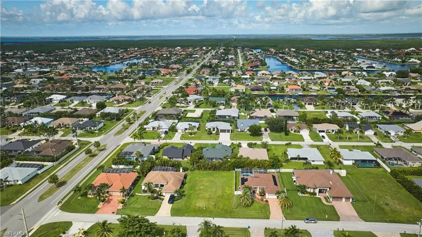 Aerial view of property and surrounding area featuring a nearby body of water and nearby suburban area