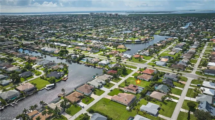 Aerial view of property's location featuring a nearby body of water and nearby suburban area
