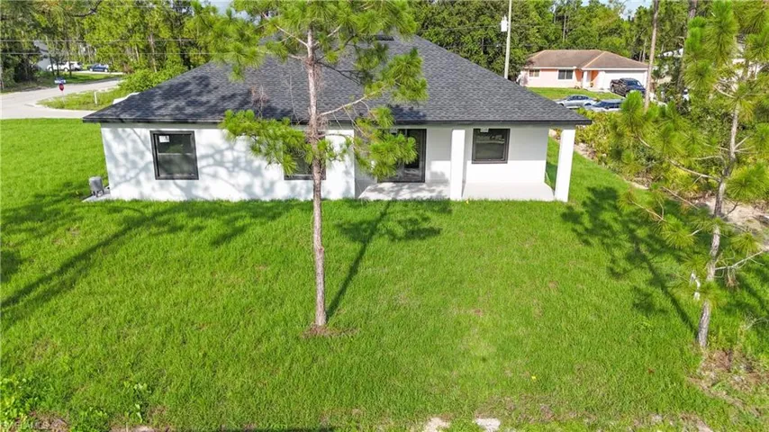Back of property with roof with shingles, stucco siding, a yard, and a patio area