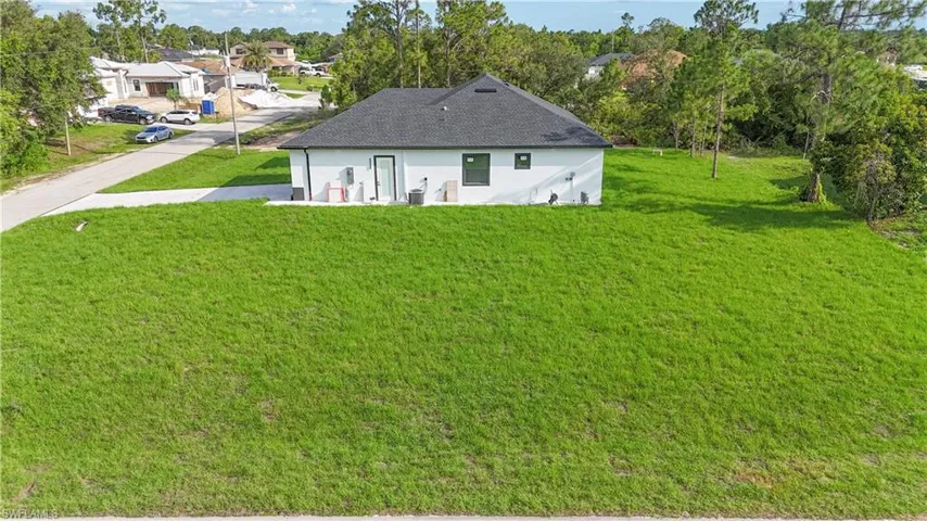 Rear view of property with a lawn, a shingled roof, and stucco siding