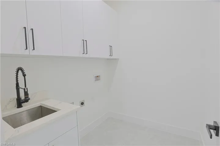 Washroom with electric dryer hookup, cabinet space, washer hookup, and light marble finish floors