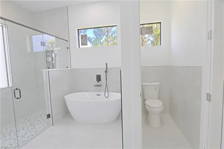 Bathroom featuring a freestanding tub, a shower stall, and tile walls