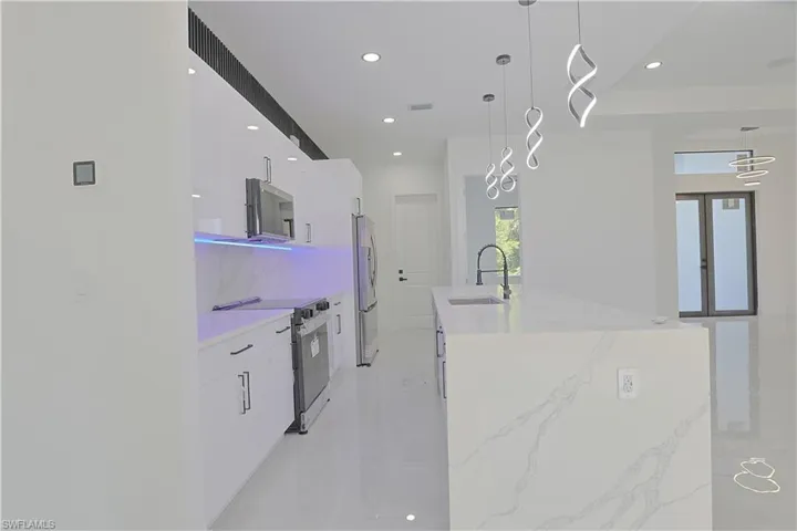 Kitchen featuring stainless steel appliances, modern cabinets, white cabinets, recessed lighting, and decorative backsplash