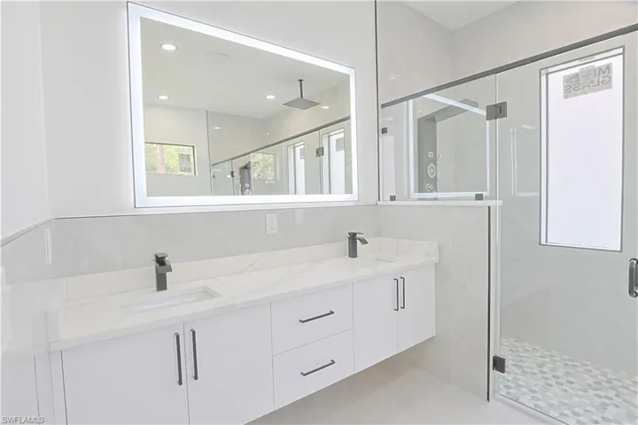 Full bath with double vanity, a shower stall, and recessed lighting