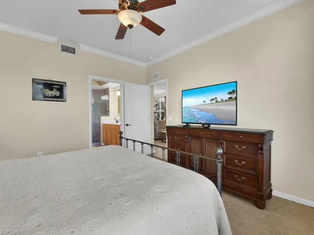 Carpeted bedroom featuring crown molding and a ceiling fan