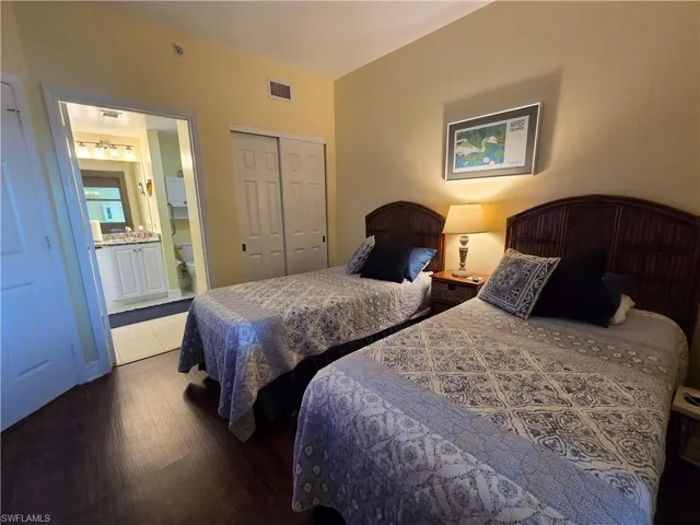 Bedroom featuring dark wood-finish flooring, light-colored walls, and a sliding door closet